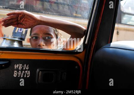 Un jeune mendiant frappant à la fenêtre et des taxis dans une rue animée de Kolkata, en Inde. Banque D'Images