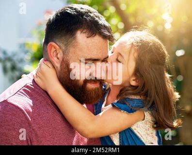 Première règle d'élever une fille l'Amour. une adorable petite fille donnant à son père un baiser à l'extérieur. Banque D'Images