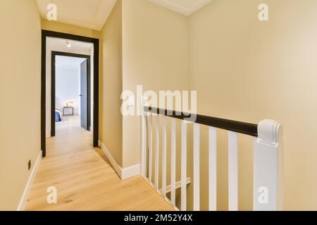 un couloir avec parquet et rambardes blanches sur l'escalier menant à une porte ouverte du salon Banque D'Images