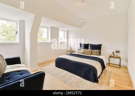 une chambre avec des murs blancs et du parquet dans la chambre, il y a un lit qui a un édredon bleu Banque D'Images