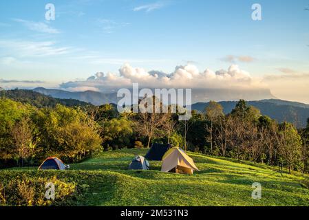 Vue sur Doi Luang Chiang Dao, la troisième plus haute montagne de Thaïlande, vue avec des nuages spectaculaires et un ciel coloré avec tentes de camping en premier plan Banque D'Images