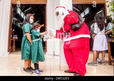 Yogyakarta, Indonésie. 25th décembre 2022. Un homme portant le costume du Père Noël remet des cadeaux aux enfants lors de la célébration de Noël à l'église Kristus Raja Baciro à Yogyakarta, Indonésie, le 25 décembre 2022. Credit: Agung Supriyanto/Xinhua/Alamy Live News Banque D'Images