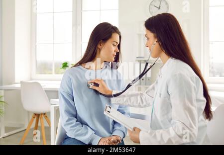 Une femme médecin écoute la respiration du patient en appliquant un stéthoscope sur sa poitrine. Banque D'Images