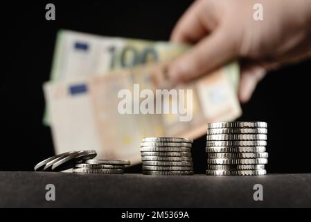 Pièces de monnaie et argent sur fond sombre. Main tenant de l'argent pour des prêts pour des investissements prévus dans un futur concept. Banque D'Images