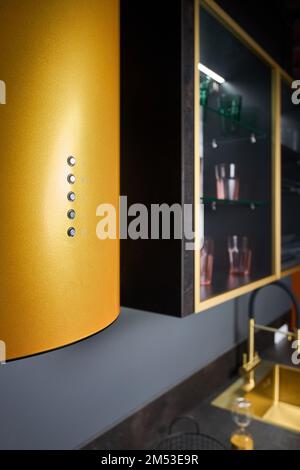 Hotte ou hotte aspirante moderne de gamme cylindrique dorée dans la cuisine pour le design d'une cuisinière îlot, panneau de commande vue rapprochée sur la cuisine hors foyer Banque D'Images