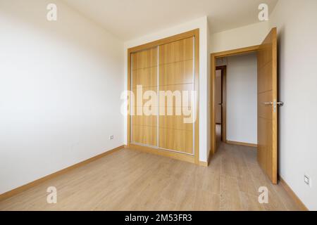 chambre avec armoire intégrée à deux sections avec grandes portes coulissantes en chêne, parquet et porte d'accès du même matériau Banque D'Images