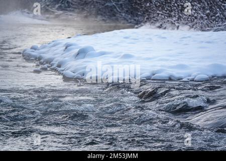 Rivière froide d'hiver, vapeur visible au-dessus de l'eau, arbres sombres sur le côté Banque D'Images