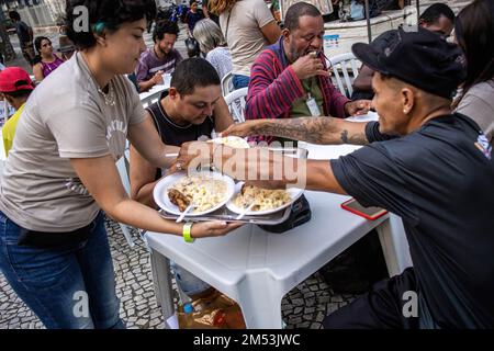 Rio de Janeiro, Brésil. 24th décembre 2022. Les bénévoles servent le dîner de charité pour les sans-abri le soir de Noël. Dîner de Noël pour les sans-abri dans le centre de Rio de Janeiro. 150 volontaires sous l'église baptiste se sont mobilisés sur la place Largo de Carioca pour servir le dîner de Noël pour les personnes qui vivent dans les rues du centre de Rio de Janeiro. Depuis 15 ans, l'église baptiste organise cet événement pour les sans-abri. Dans la deuxième plus grande ville du Brésil, environ 15 000 000 personnes vivent dans les rues sans domicile. Crédit : SOPA Images Limited/Alamy Live News Banque D'Images