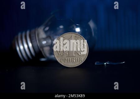 Ampoule cassée avec des morceaux de verre et 1 Ukraine pièce de Hryvnia. Concept des prix de l'électricité et de la crise de l'électricité en Ukraine Banque D'Images