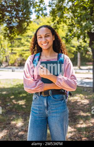 Femme étudiante noire souriante tenant des livres dans le parc. Confiance en soi saine. Génération Centennial Banque D'Images