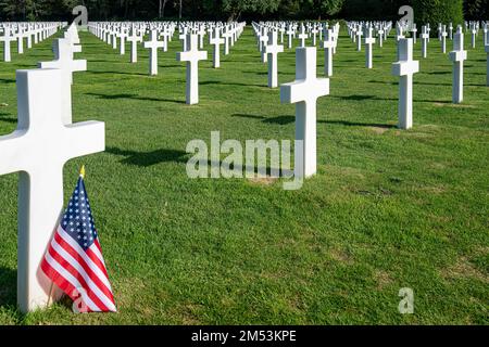 Un drapeau américain debout sur la pierre tombale d'un soldat tué au cimetière de guerre en Normandie Banque D'Images