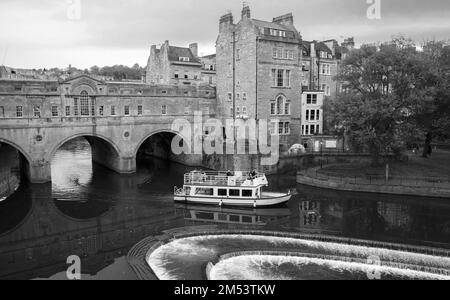 Bath, Royaume-Uni - 1 novembre 2017: Petit bateau à passagers va près du pont Pulteney du 18th siècle, vue sur la vieille ville de Bath, phot noir et blanc Banque D'Images