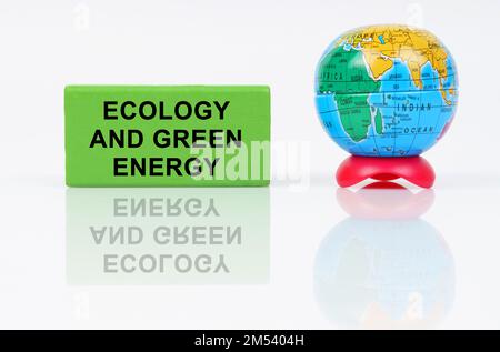 Concept écologique. Sur une surface réfléchissante se trouve un globe et un signe vert avec l'inscription Ecologie et énergie verte Banque D'Images