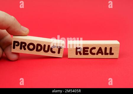 Concept d'entreprise. Sur fond rouge, blocs de bois, l'un d'eux à la main. Les blocs sont écrits - RAPPEL DE PRODUIT Banque D'Images