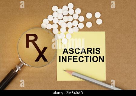 Concept médical. Sur la table sont des pilules, une loupe, des crayons et un autocollant avec l'inscription - infection Ascaris Banque D'Images