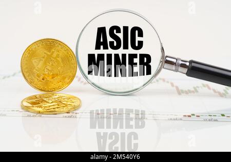 Concept d'entreprise et de technologie. Il y a des bitcoins sur la carte et il y a une loupe avec l'inscription - ASIC Miner Banque D'Images