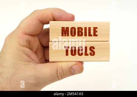 Concept d'entreprise. Sur fond blanc, une main qui tient des blocs de bois avec l'inscription - Mobile Tools Banque D'Images