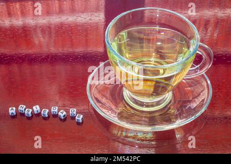 Goiania, Goiás, Brésil – 25 décembre 2022 : une tasse de thé en verre sur une table à surface brillante et le mot « anxiété » écrit en briques. Banque D'Images