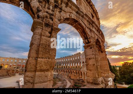 L'Amphithéâtre Pula d'Istrie, en Croatie pendant la soirée, le ciel se transforme en une étonnante nuance de rose et d'orange, créant une toile de fond à couper le souffle Banque D'Images