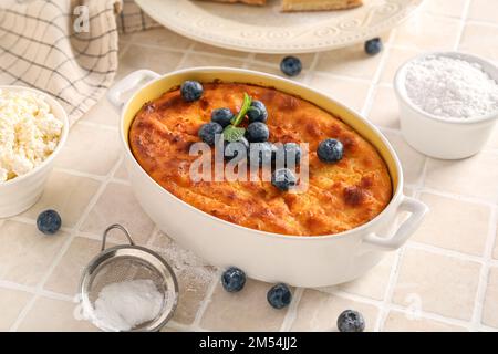 Tarte au fromage délicieuse avec myrtille fraîche sous forme de cuisson et ingrédients sur table en carreaux blancs Banque D'Images