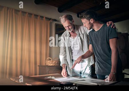 Obtenir des conseils d'un ancien pro. un père et son fils qui travaillent sur un design pour leur entreprise familiale à la maison. Banque D'Images