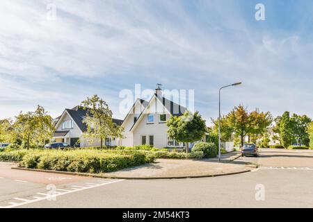 une rue avec des maisons et des voitures garées dans le parking de chaque côté de la route il y a un ciel bleu rempli de blanc Banque D'Images