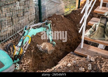 Une minipelle creuse une tranchée pour poser les tuyaux. Gros plan d'une pelle hydraulique creusant une tranchée profonde. Une pelle hydraulique creuse une tranchée dans la campagne pour déposer un Banque D'Images