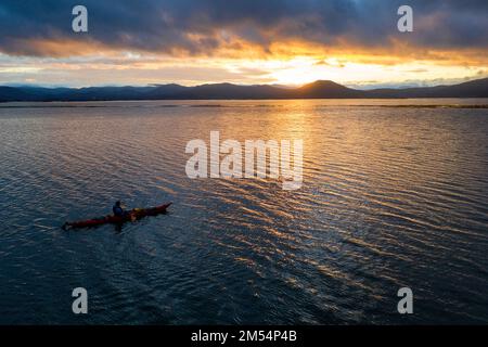 Vue aérienne d'un homme local en kayak, profitant d'un beau lever de soleil le matin d'hiver froid tout en pagayant sur le lac intermittent en slovénie Banque D'Images