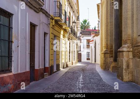 Ruelle étroite avec des maisons pittoresques et des murs d'église médiévale dans la ville touristique d'Ecija, Séville. Banque D'Images