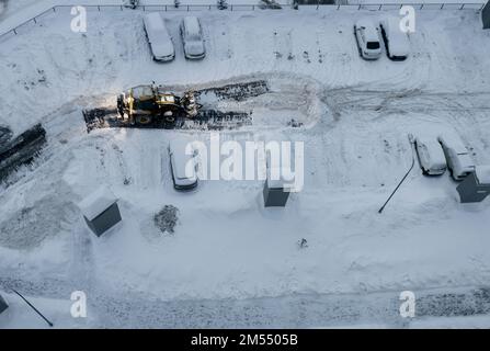 Le chargeur du tracteur charge de la neige sale dans le camion à benne basculante. Nettoyage des rues de la ville, déneigement et déglaçage après de fortes chutes de neige. Chasse-neige nettoyer les pavés Banque D'Images