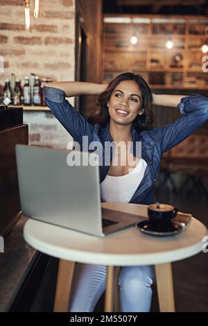 La vie est tellement plus facile quand vous vous détendez. une jeune femme détendue utilisant son ordinateur portable dans un café. Banque D'Images