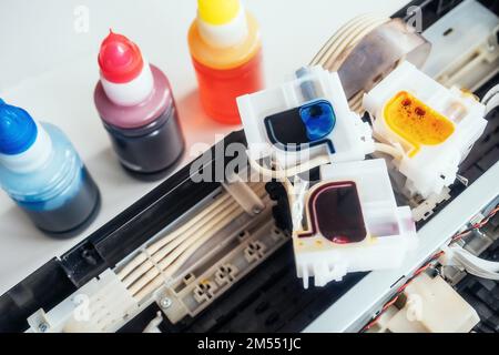Remplissage de l'imprimante à jet d'encre avec de l'encre de couleur. Service de réparation et d'entretien de l'équipement et de l'équipement de bureau. Arrière-plan. Vue du dessus. Banque D'Images