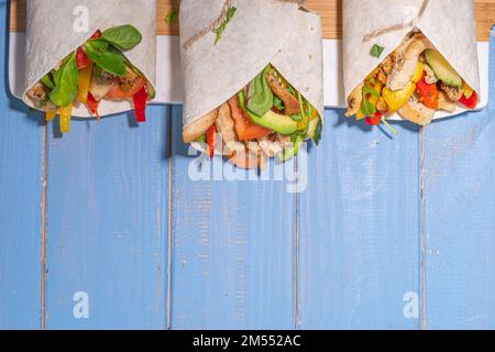 Classique rue nourriture shawarma ou burrito, sandwich sain enveloppé dans la tortilla pain plat avec viande de poulet frite, légumes frais, sauce, sur b vif Banque D'Images