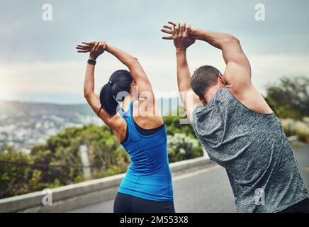 Ne laissez pas votre partenaire s'exercer avant de vous étirer. un couple méconnaissable s'entraîner pour un marathon en plein air. Banque D'Images