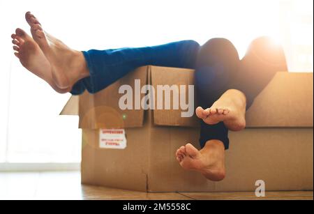 Tout était prêt à l'emploi. Un jeune couple inidentifiable allongé dans une boîte avec ses pieds collés. Banque D'Images