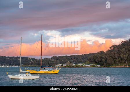 De grands nuages colorés boursouflés reflétant la lumière du soleil de la fin de l'après-midi se roulent vers le nord en direction d'Ettalong Beach, en traversant Broken Bay en Nouvelle-Galles du Sud, en Australie Banque D'Images