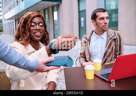 Femme effectuant un paiement sans contact avec une montre intelligente dans un café. Banque D'Images