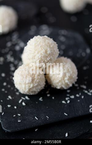 Pralines de noix de coco blanches sur fond de granit noir. Mise au point sélective, faible profondeur de champ Banque D'Images