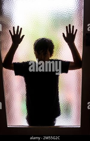 Silhouette de garçon contre la porte en verre dépoli. Sydney, Nouvelle-Galles du Sud, Australie Banque D'Images