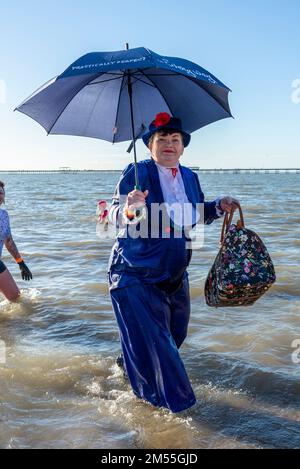 Jubilee Beach, Marine Parade, Southend on Sea, Essex, Royaume-Uni. 26th décembre 2022. Comme c'est devenu une tradition en bord de mer, un plongeon du lendemain de Noël a eu lieu dans l'estuaire de la Tamise à Southend on Sea, près de l'embarcadère de la ville, qui a permis de recueillir des fonds pour l'établissement national de la Royal Lifeboat local. Environ 400 personnes ont pris à l'eau qui était d'environ 6 degrés Celsius. Beaucoup des braves nageurs portaient une tenue de fête et une robe de fantaisie. Une femme portant le costume de Mary Poppins quitte l'eau Banque D'Images