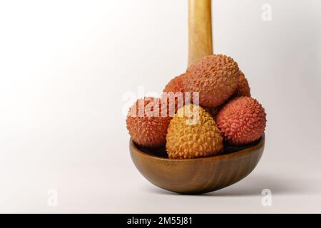 lychees frais dans une cuillère en bois isolée sur fond blanc Banque D'Images