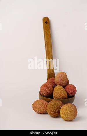 lychees frais dans une cuillère en bois isolée sur fond blanc Banque D'Images