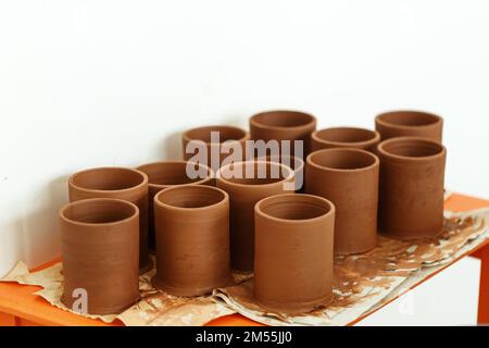 Ensemble de pots d'argile traditionnels placés sur la table en poterie, pas encore sec Banque D'Images