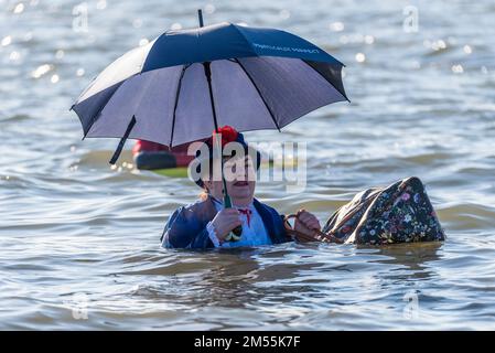 Jubilee Beach, Marine Parade, Southend on Sea, Essex, Royaume-Uni. 26th décembre 2022. Comme c'est devenu une tradition en bord de mer, un plongeon du lendemain de Noël a eu lieu dans l'estuaire de la Tamise à Southend on Sea, près de l'embarcadère de la ville, qui a permis de recueillir des fonds pour l'établissement national de la Royal Lifeboat local. Environ 400 personnes ont pris à l'eau qui était d'environ 6 degrés Celsius. Bon nombre des braves nageurs portaient une tenue de fête. Le bateau de sauvetage RNLI était à portée de main pour la sécurité. Femme portant le costume de Mary Poppins Banque D'Images