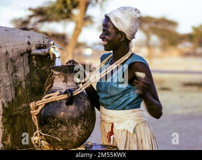 Éthiopie, 1970s ans, Adami Tulu, femme souriante qui recueille de l'eau au point d'eau communal, coucher du soleil, région d'Oromia, Afrique de l'est, Banque D'Images