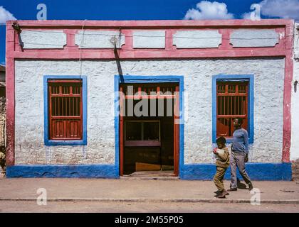 Éthiopie, 1970s ans, Harar, homme et garçon marchant devant une maison blanche rose et bleue, région de Harari, Afrique de l'est, Banque D'Images