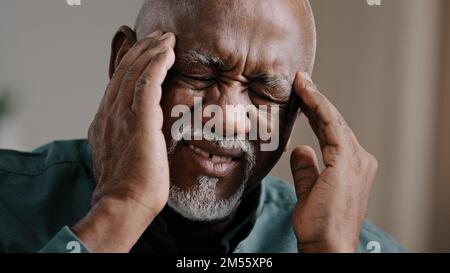 Gros plan visage triste âgé africain américain homme se sentir mal de tête migraine chronique malsain multiracial grand-père massing temples malsains d'âge moyen Banque D'Images
