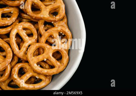 Gros plan, bretzels dans une plaque sur fond noir. Banque D'Images