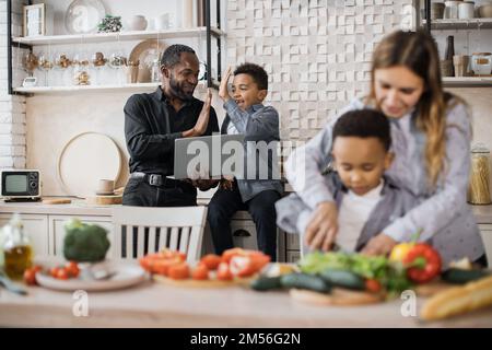 Concentrez-vous sur l'amour du père africain et petit garçon enfant trouver la recette de repas de vacances et de donner haut cinq. Bonne mère enseigner petit fils de préchooler hacher des légumes préparer la salade pour le déjeuner ensemble. Banque D'Images