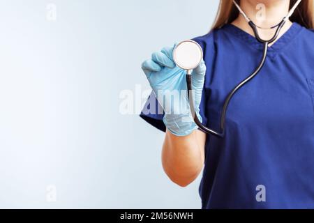 Femme médecin en uniforme avec stéthoscope sur fond bleu Banque D'Images